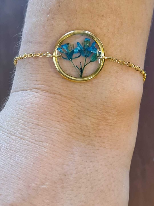Bracelet doré en résine contenant une véritable fleur séchée turquoise