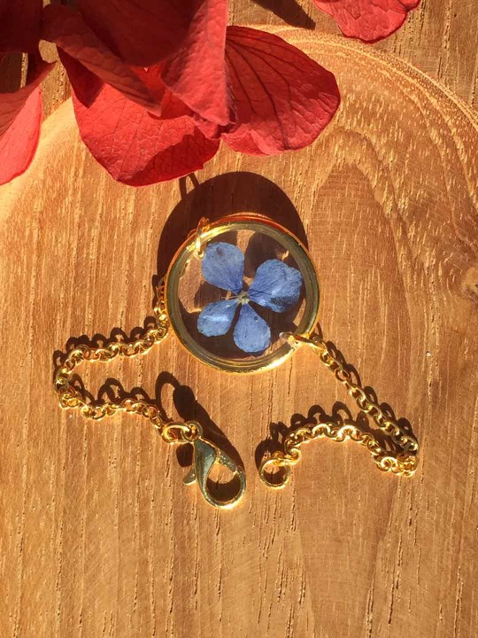 Bracelet doré en résine contenant une véritable fleur séchée bleue