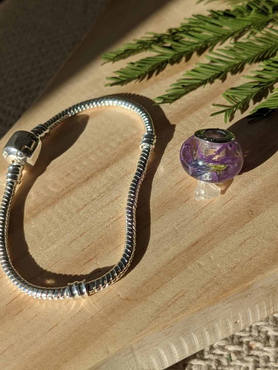 Bracelet avec charm perle en résine contenant de véritables fleurs violettes