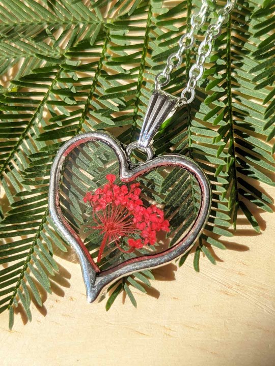 Collier coeur en résine contenant de véritables fleurs rouges