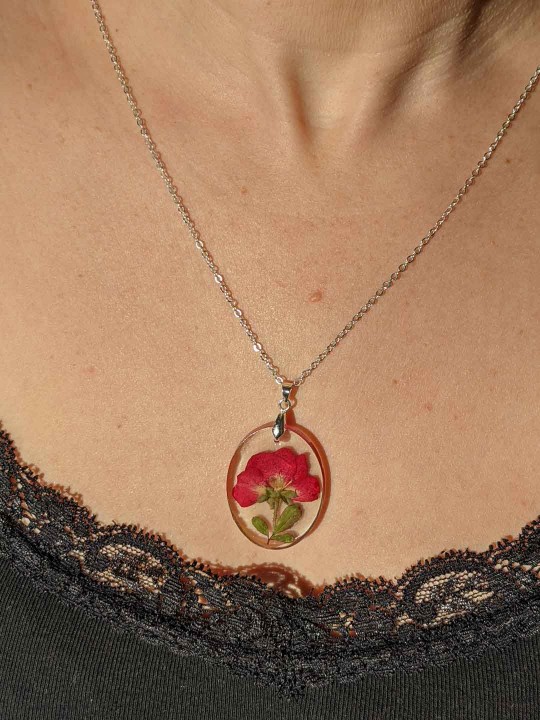 Collier ovale transparent en résine contenant une véritable rose