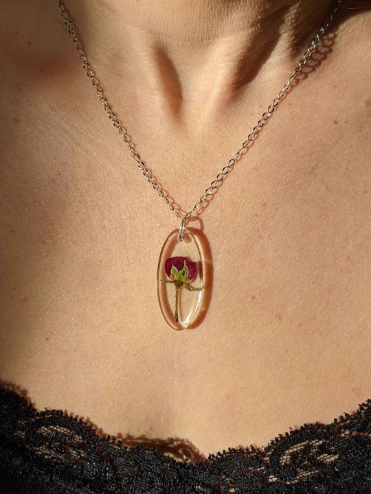 Collier ovale transparent en résine contenant une véritable rose